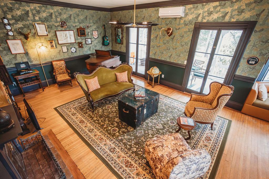 Vintage living room with patterned wallpaper, antique furniture, and a piano.