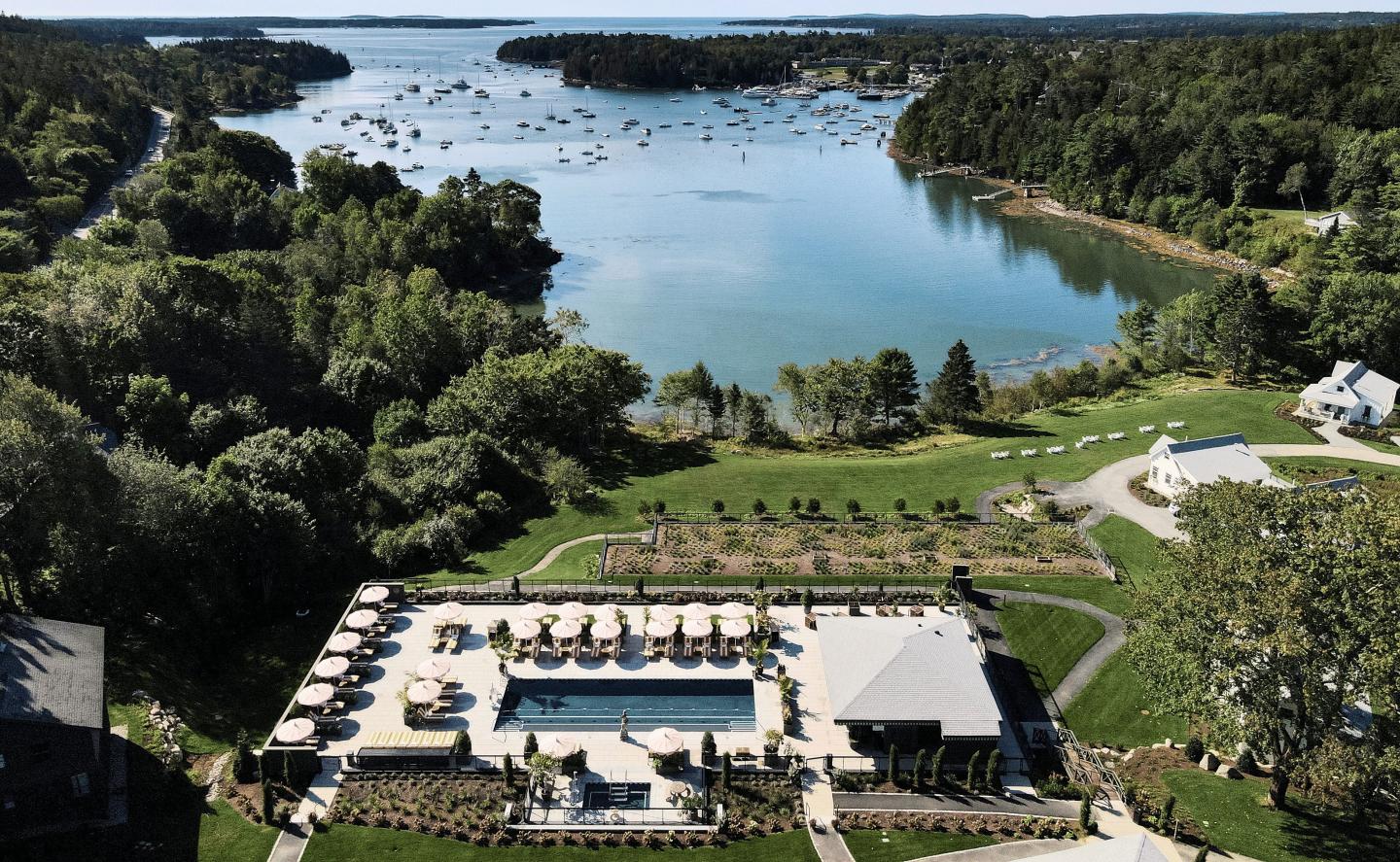 Aerial view of a resort pool, surrounded by greenery and overlooking a lake.