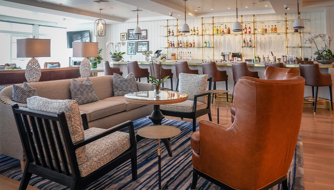 Cozy lounge with sofas, patterned cushions, and a bar in the background.