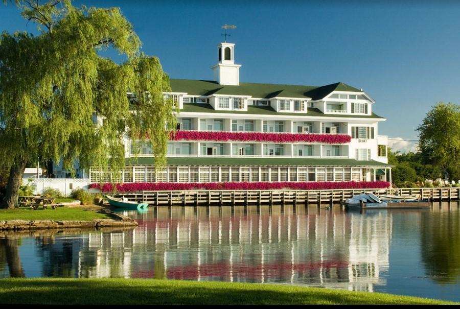 Grand hotel by a tranquil lake, under a clear blue sky.