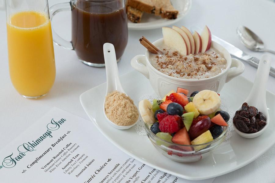 Fruit, oatmeal, and drinks on a breakfast table setting.