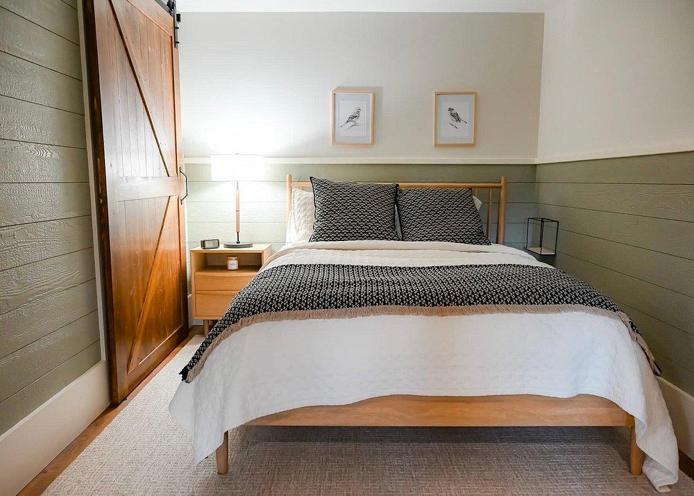 Cozy bedroom with a wooden bed, gray bedding, and framed art.
