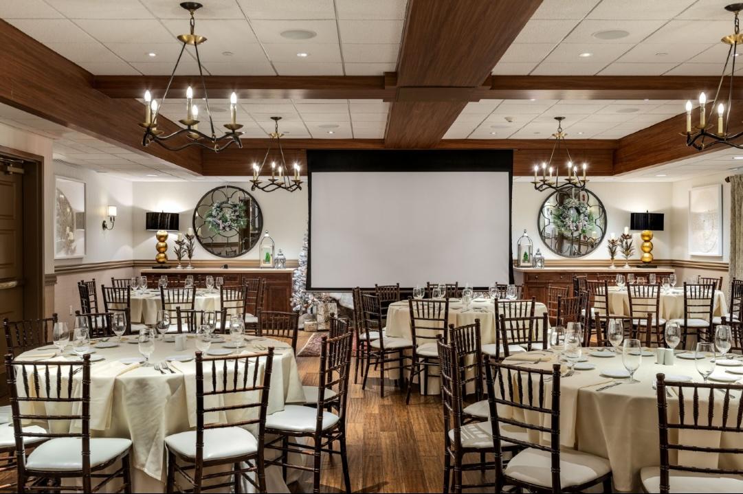 Elegant banquet hall with round tables and a large screen.