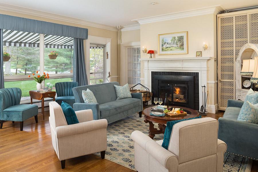 Cozy living room with sofas, armchairs, a fireplace, and large windows.