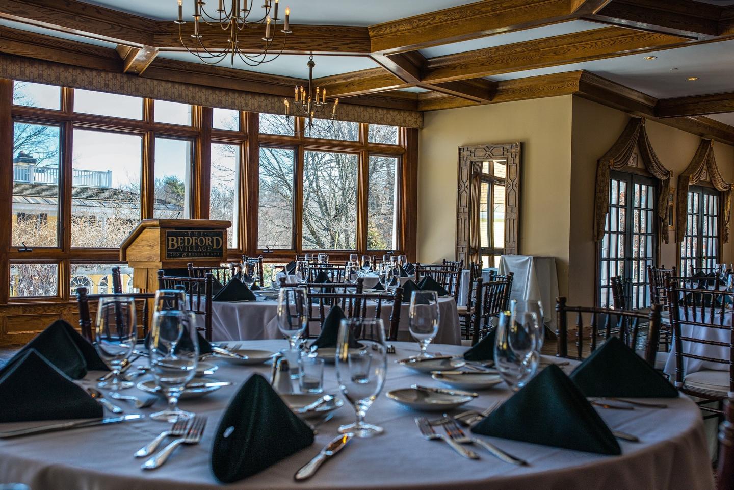 Elegant dining room with set tables and large windows.