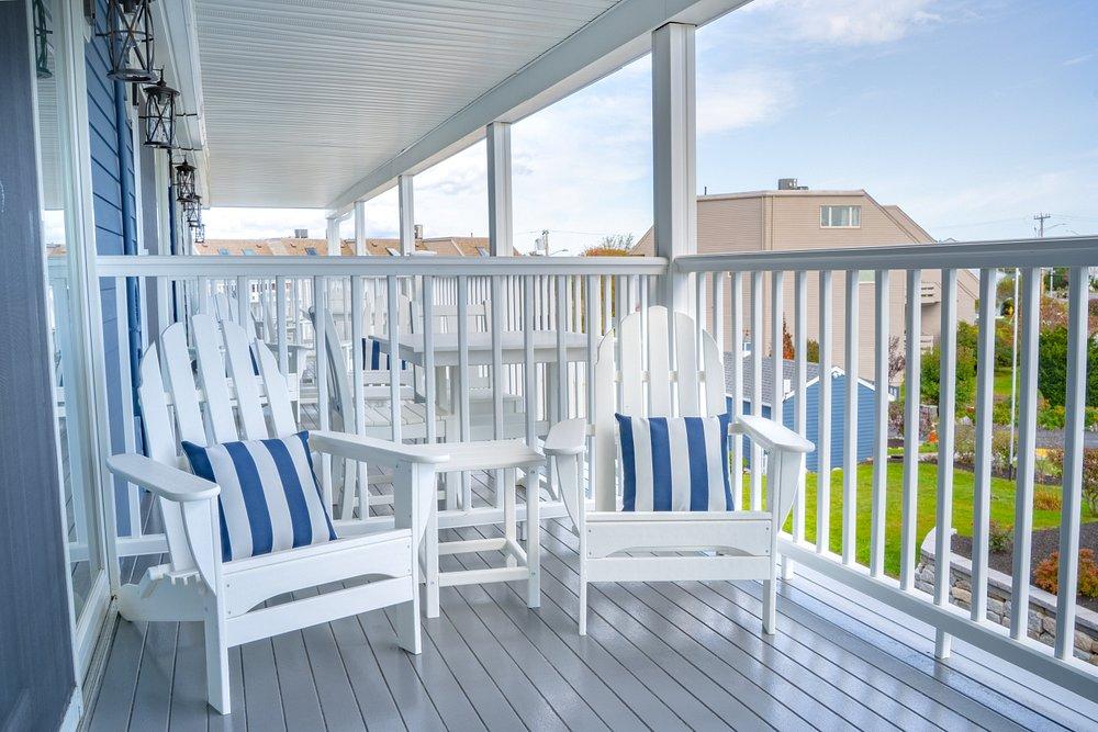 White porch chairs with blue-striped cushions on a sunny deck.