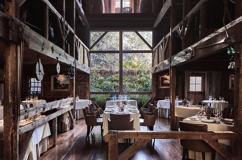 Rustic restaurant interior with large windows and wooden beams.