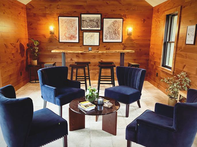 Cozy room with blue chairs, wooden walls, art, and a small bar.