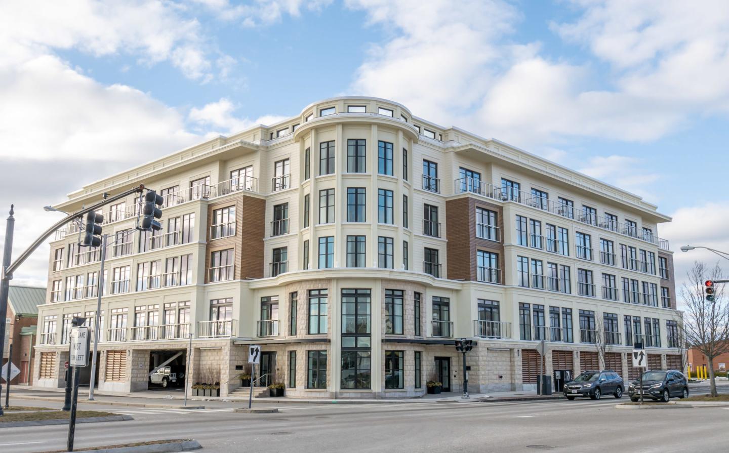 Elegant, multi-story building with large windows under a partly cloudy sky.