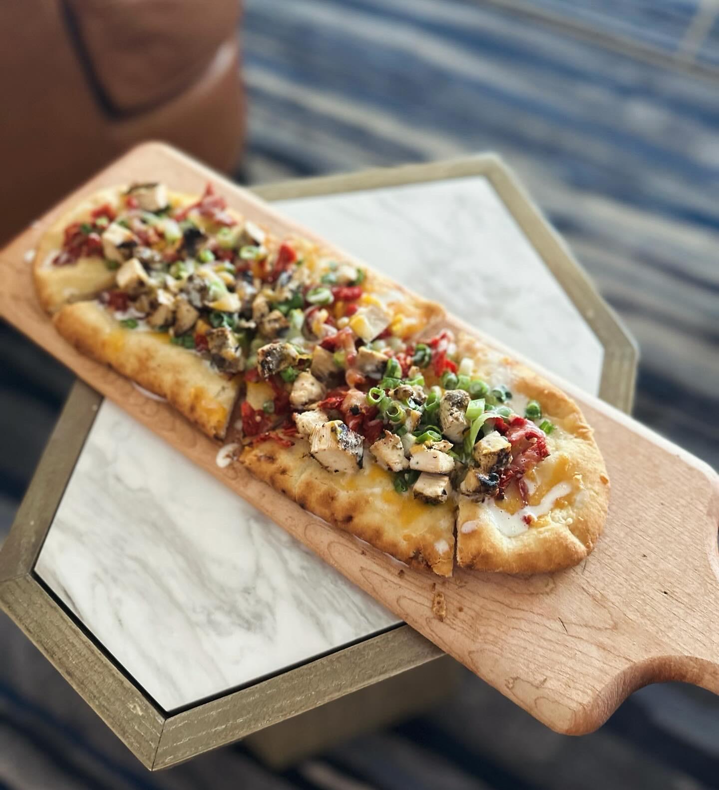 Flatbread with colorful toppings on a wooden board.