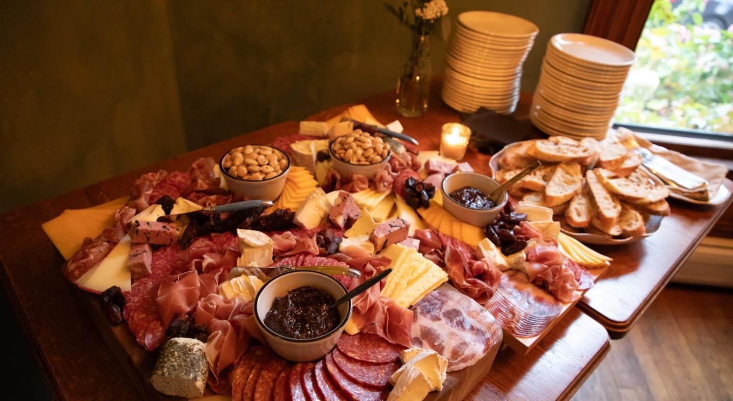 Charcuterie board with meats, cheeses, nuts, and bread on a wooden table.