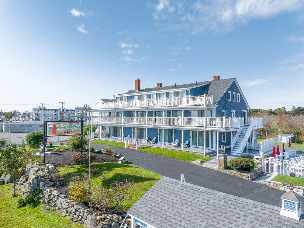 Three-story blue hotel with balconies, sunny day, clear sky.
