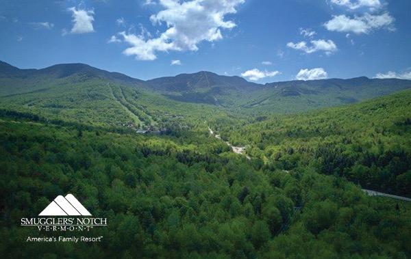 Lush green mountains under a blue sky with scattered clouds.