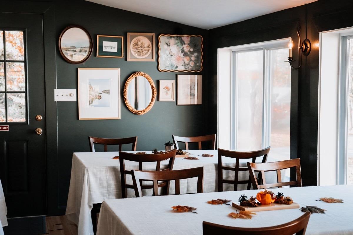 Cozy dining room with framed art, white tablecloths, and autumn decor.