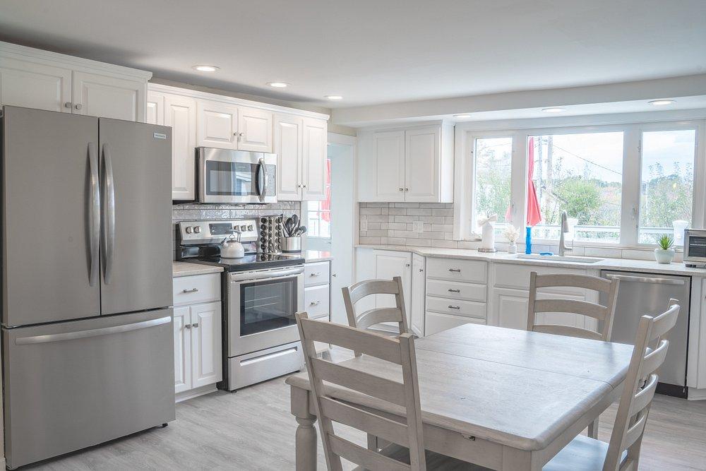 Bright kitchen with white cabinets, stainless steel appliances, and a dining table.