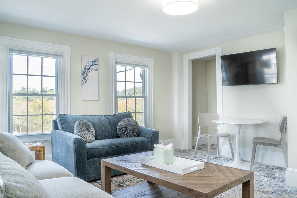 Living room with two sofas, a wall-mounted TV, and a small dining table.