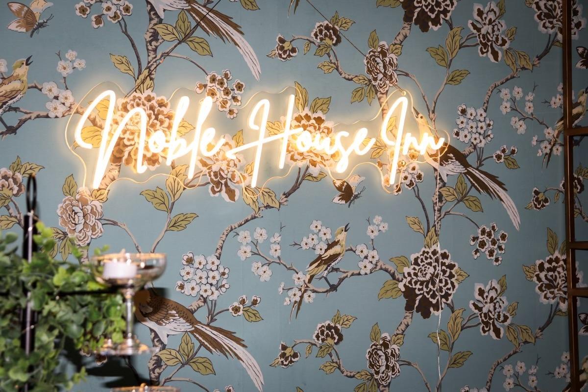Elegant floral wallpaper with "Noble House Inn" in neon script.