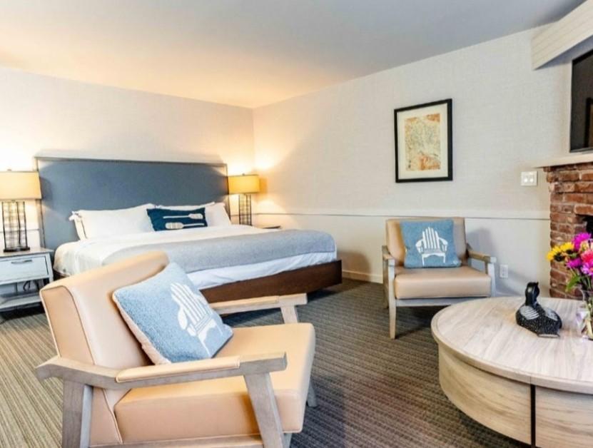 Modern hotel room with a large bed, two chairs, and a round table.