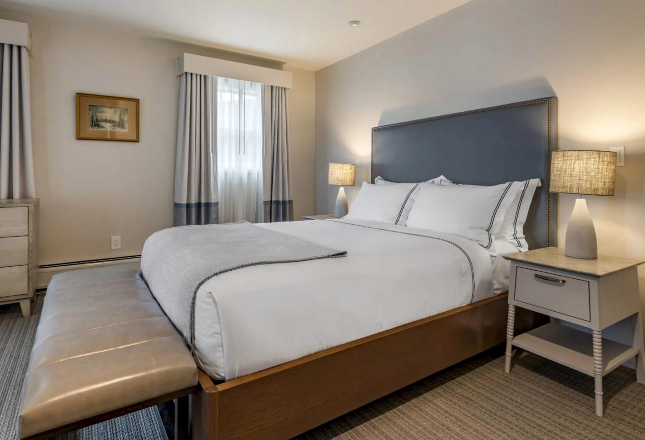 Cozy bedroom with a large bed, two lamps, and a bench at the foot.
