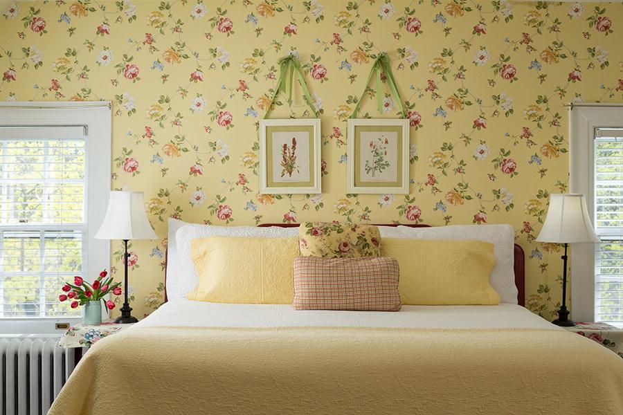 Cozy bedroom with floral wallpaper and yellow bedspread.