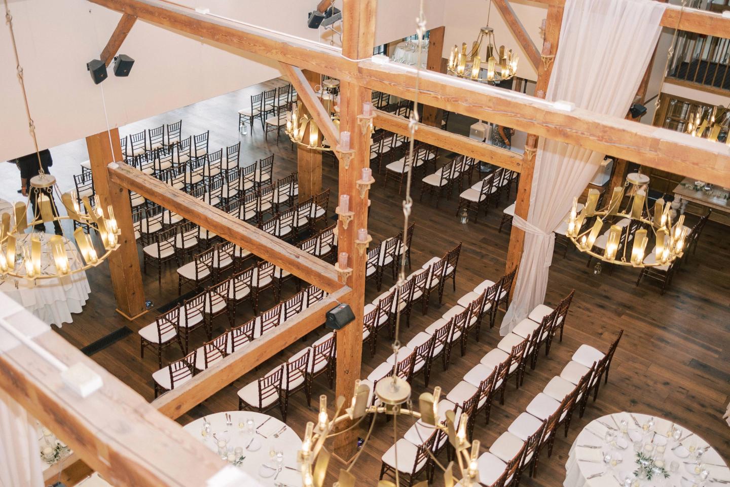 Rustic banquet hall with long tables and chandeliers.