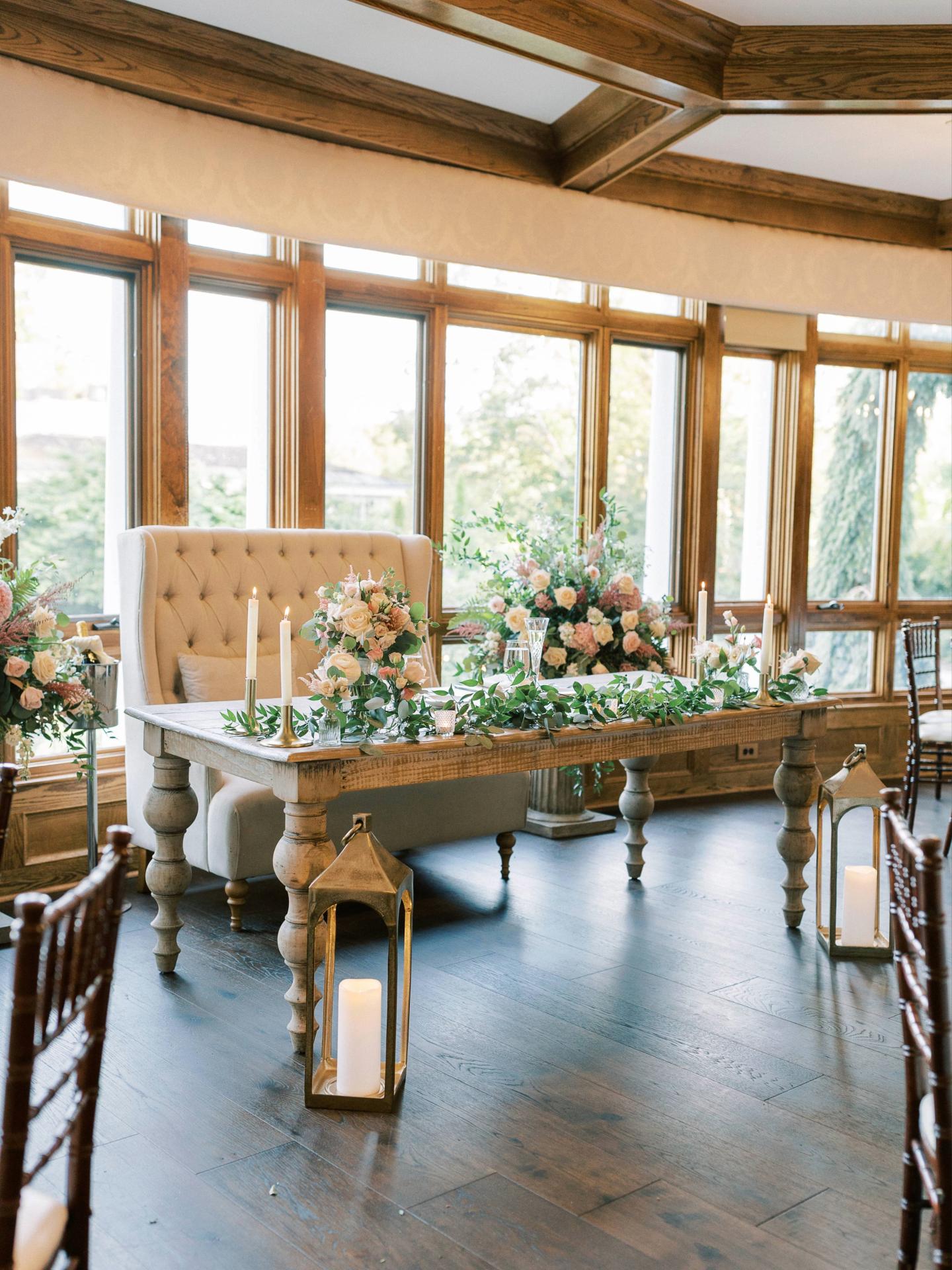 Elegant wedding table with flowers and candles by large windows.