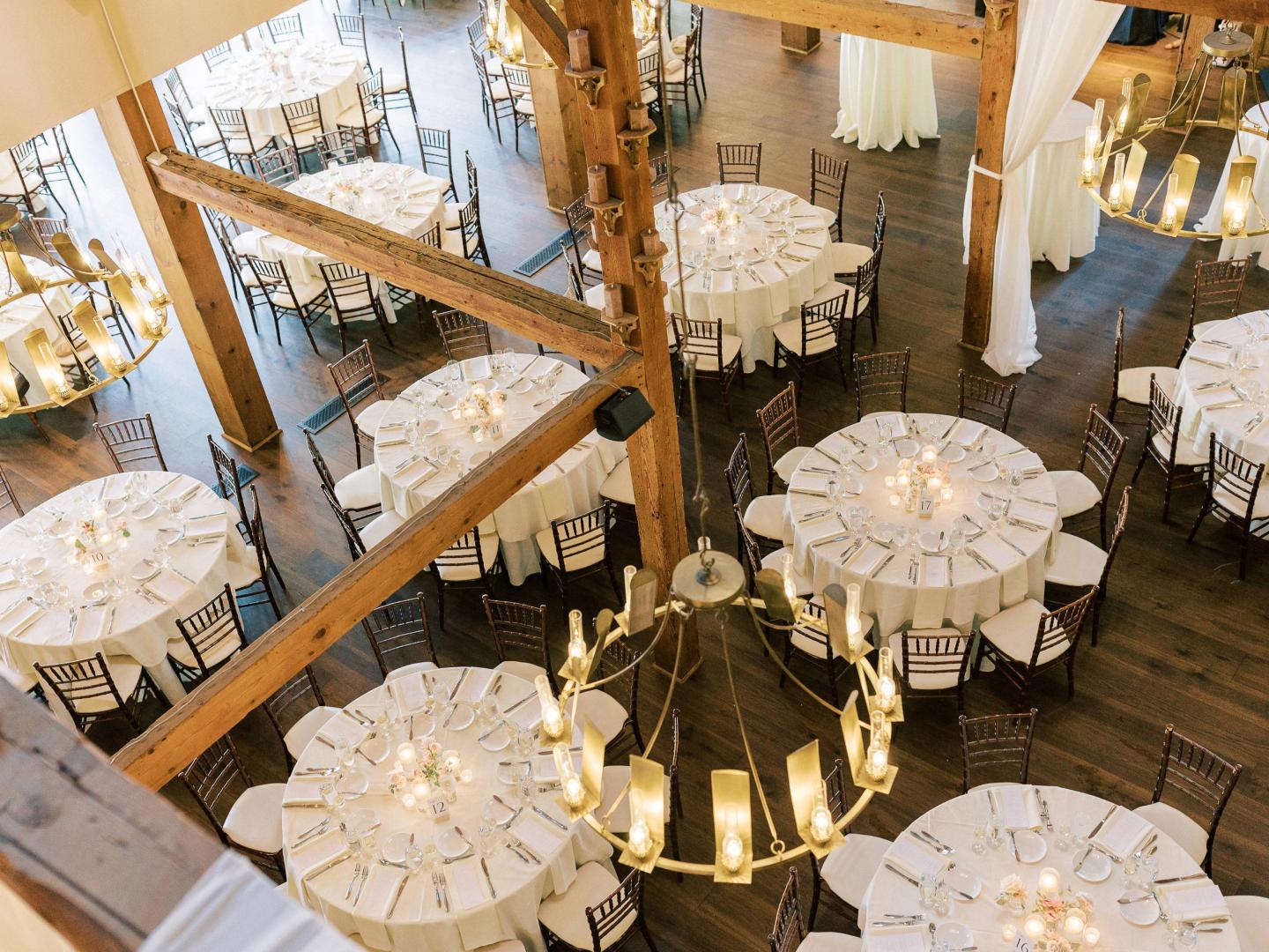 Rustic hall with round tables set for an event.