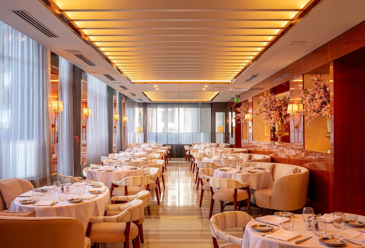 Elegant restaurant with white tablecloths, warm lighting, and mirrored walls.