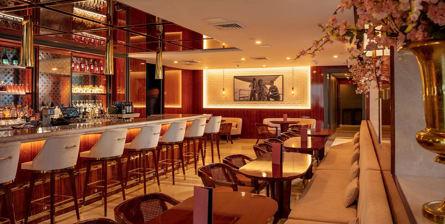 Elegant bar interior with red and gold decor, plush seating, and a well-lit counter.