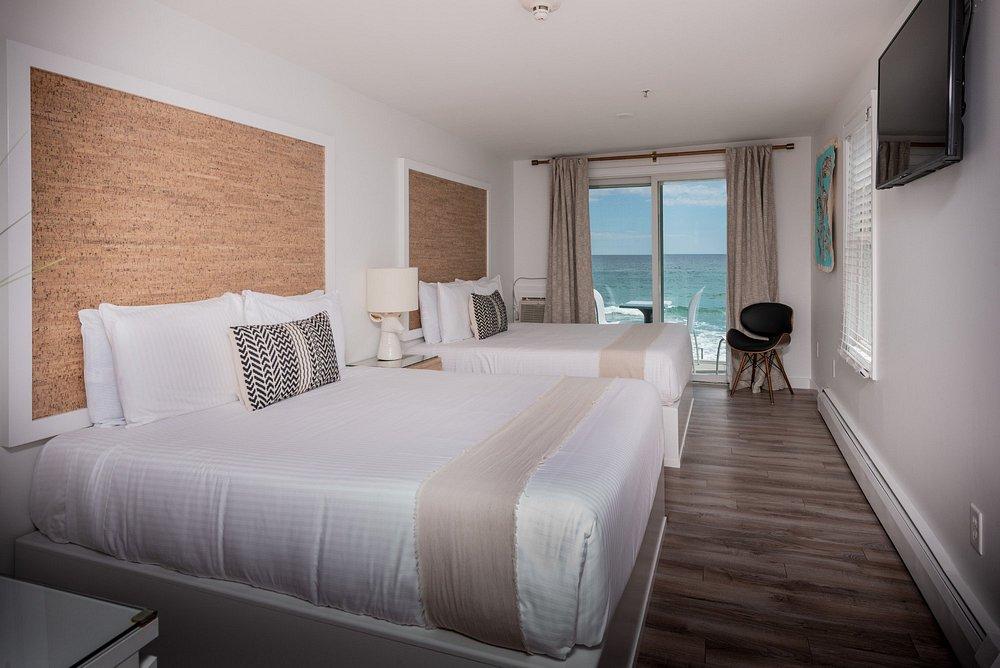 Cozy hotel room with ocean view, two beds, neutral decor.