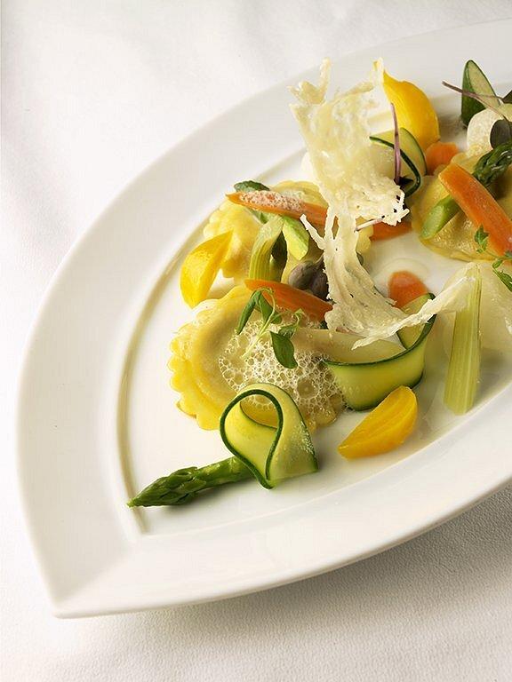 Pasta with vegetables on a white plate, garnished artistically.