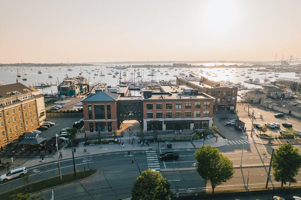 Drone Aerial view of a waterfront cityscape at sunset with boats in the harbor.