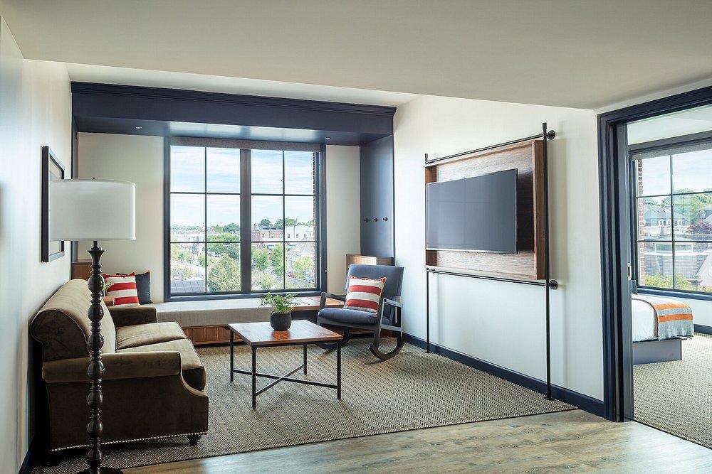 Stylish living room with sofa, window seat, TV, and access to bedroom.