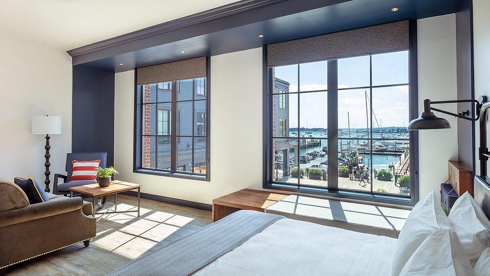 Bright room with a bed, sofa, and large windows overlooking a marina.