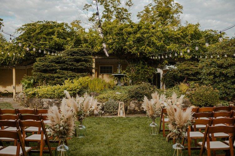 Garden wedding setting with chairs, flowers, and greenery.
