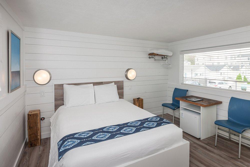 Modern hotel room with a bed, two chairs, and window view.