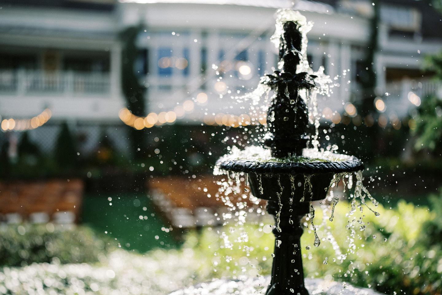 A black fountain with water droplets sparkling in sunlight.