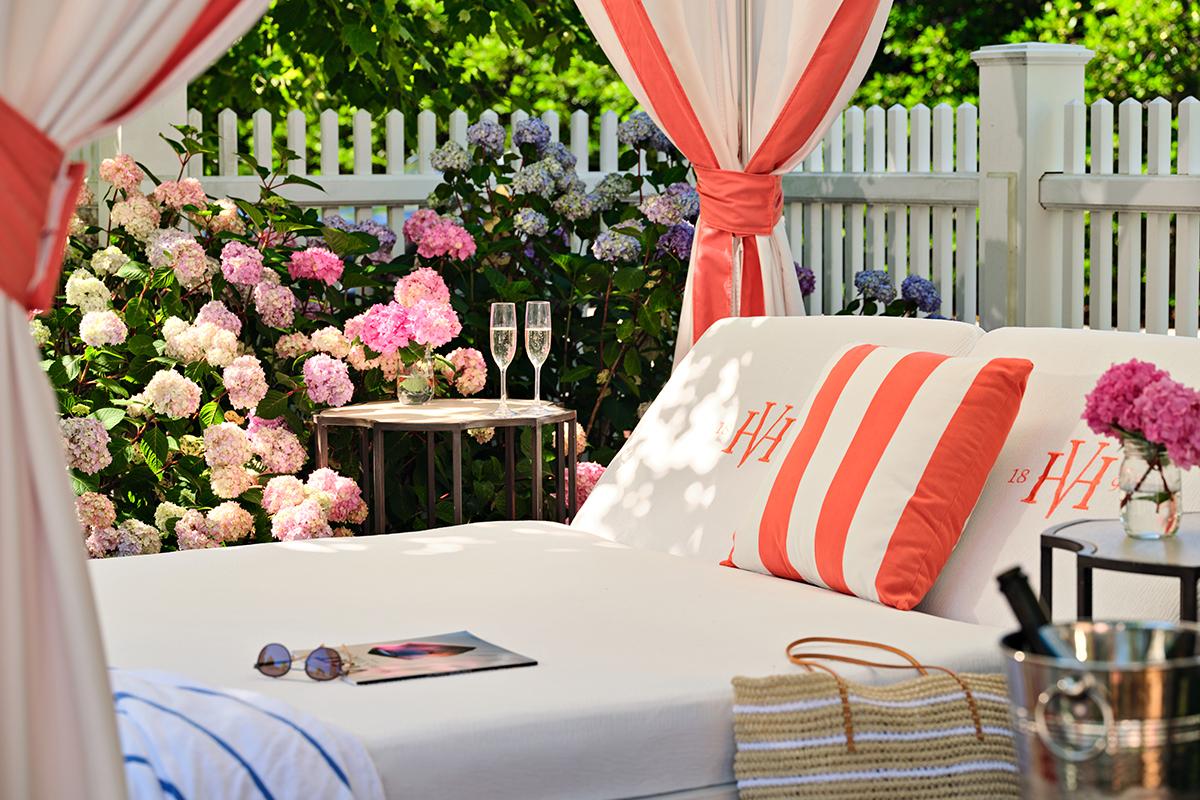 Outdoor lounge with cushions, flowers, and champagne glasses on a table.