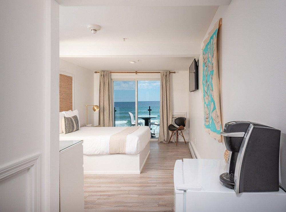 Hotel room with ocean view, bed, map on wall, and coffee maker.