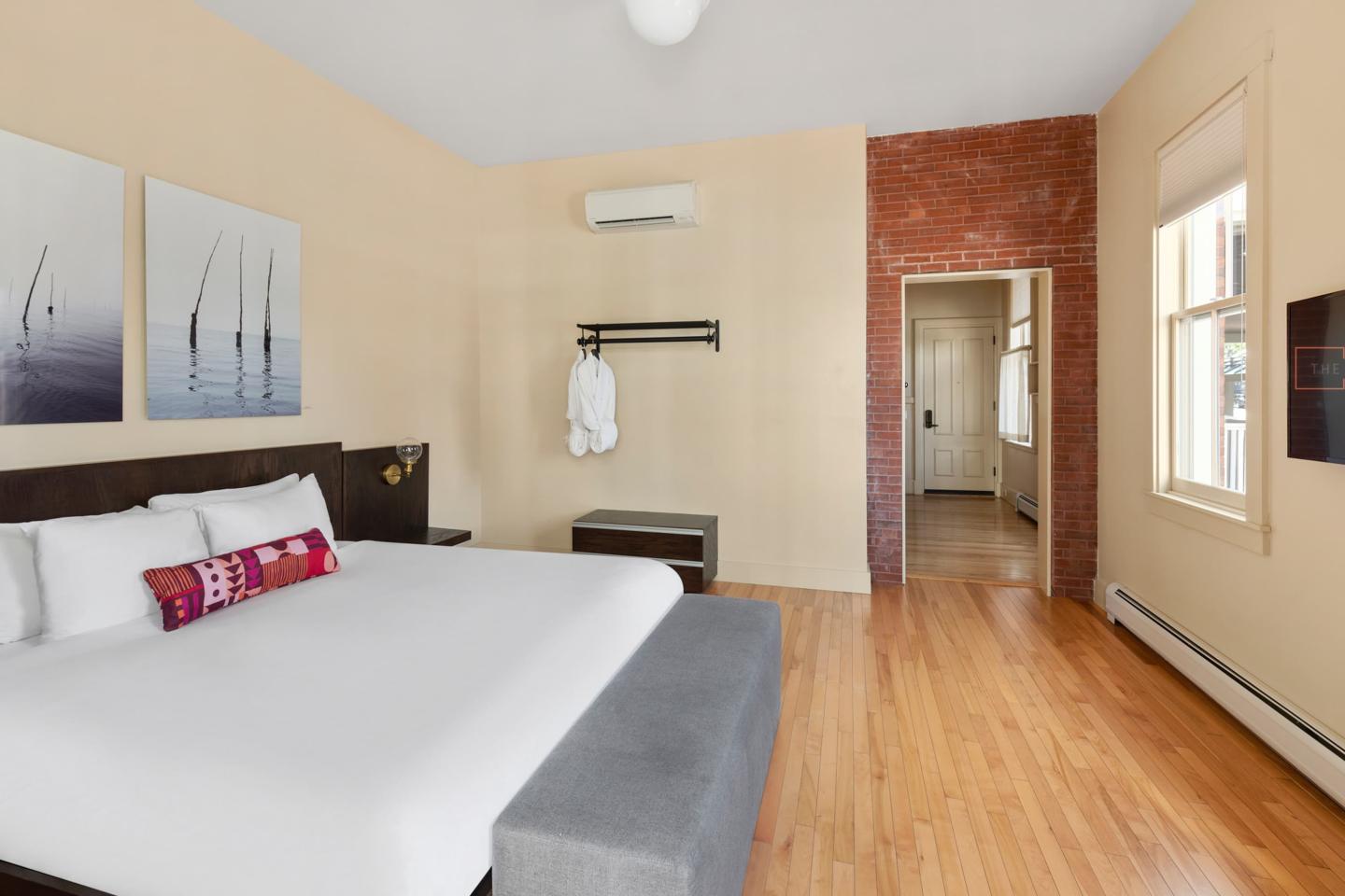 Spacious bedroom with a large bed, wood floors, and natural light.