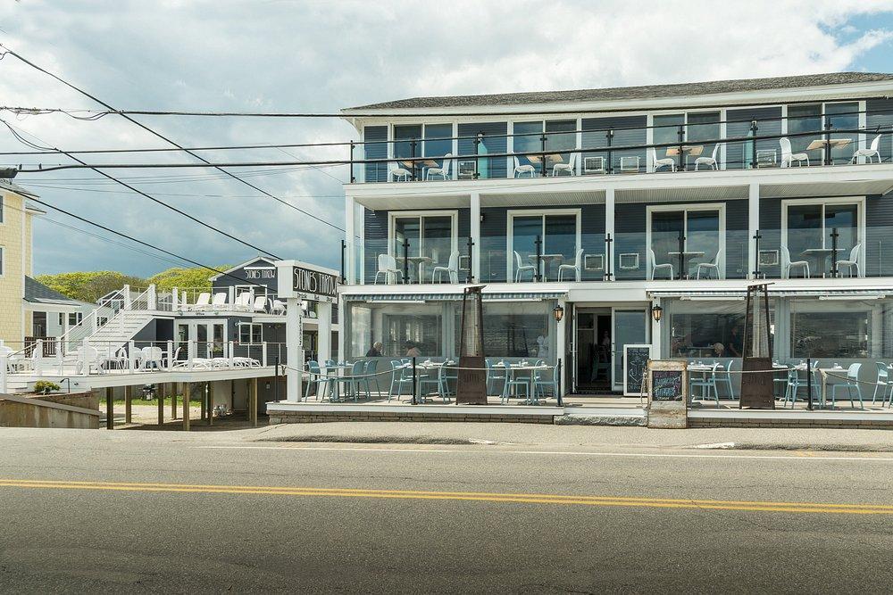 Modern three-story beachfront building with large windows and balconies.