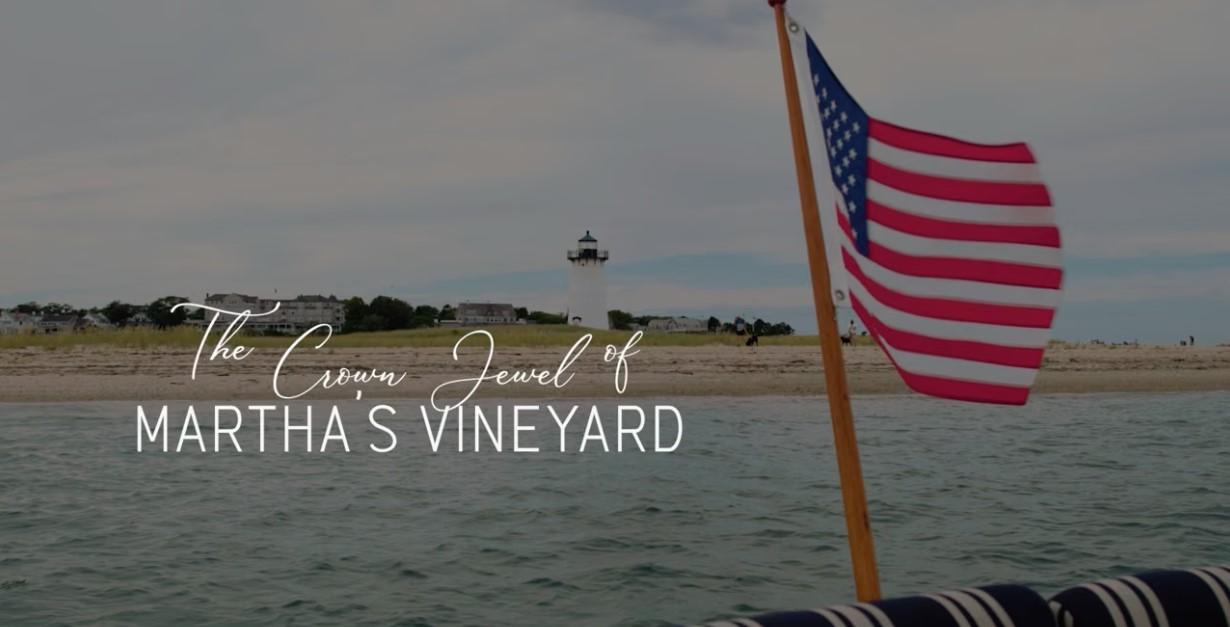 American flag on a boat with lighthouse in the distance.