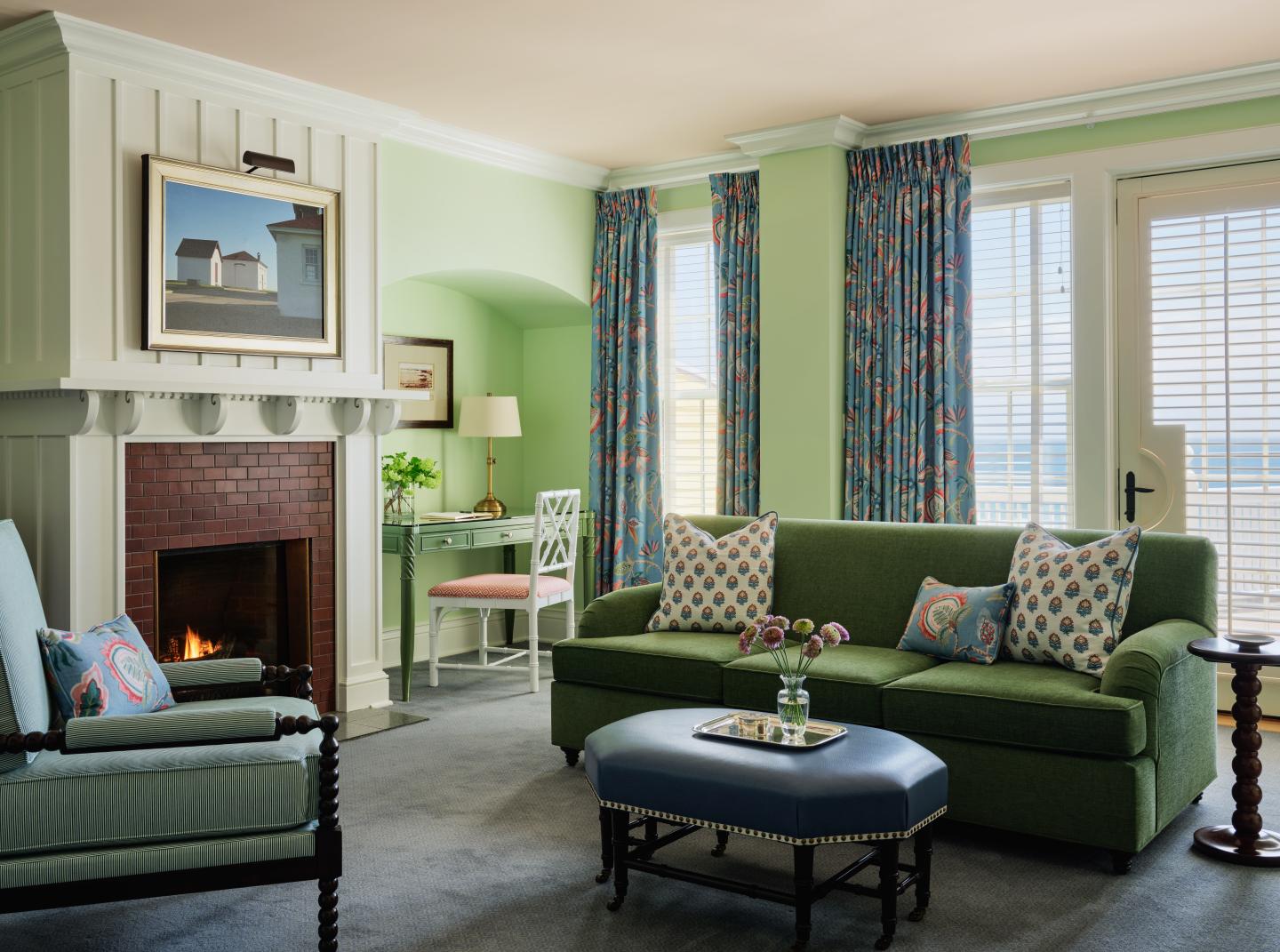 Cozy living room with green sofa, fireplace, and floral curtains.
