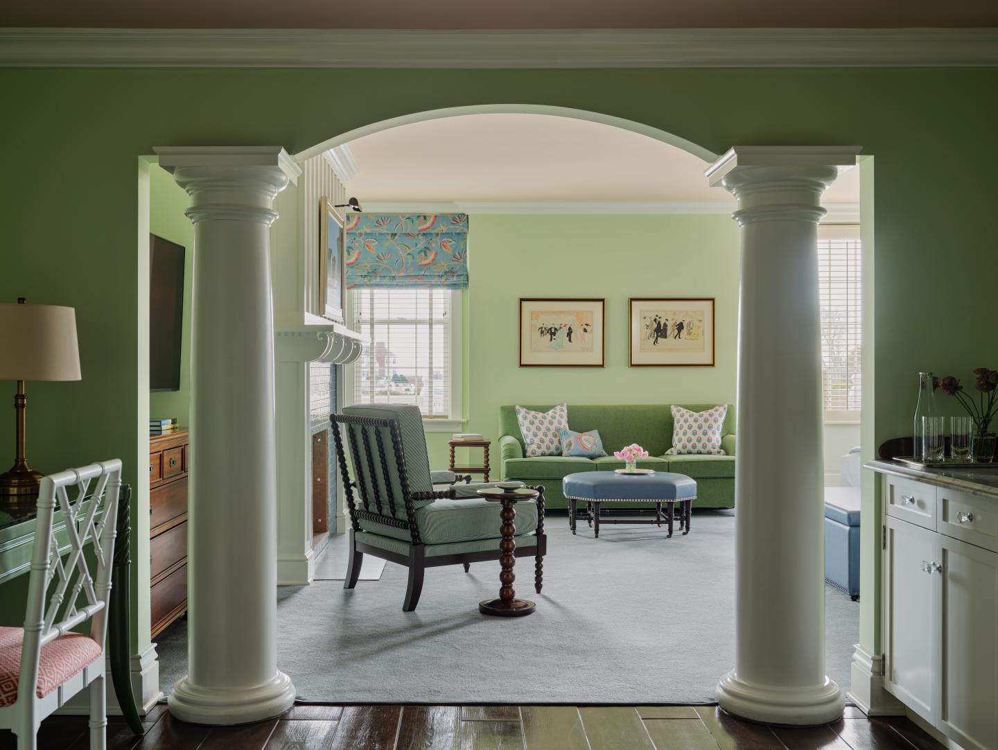 Elegant living room with green walls, archway, and column pillars.