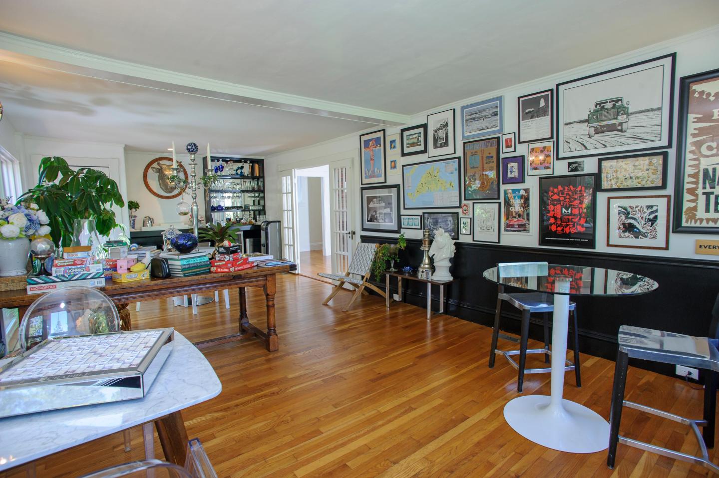 Breakfast room with art-filled walls, plants, and wooden floor.