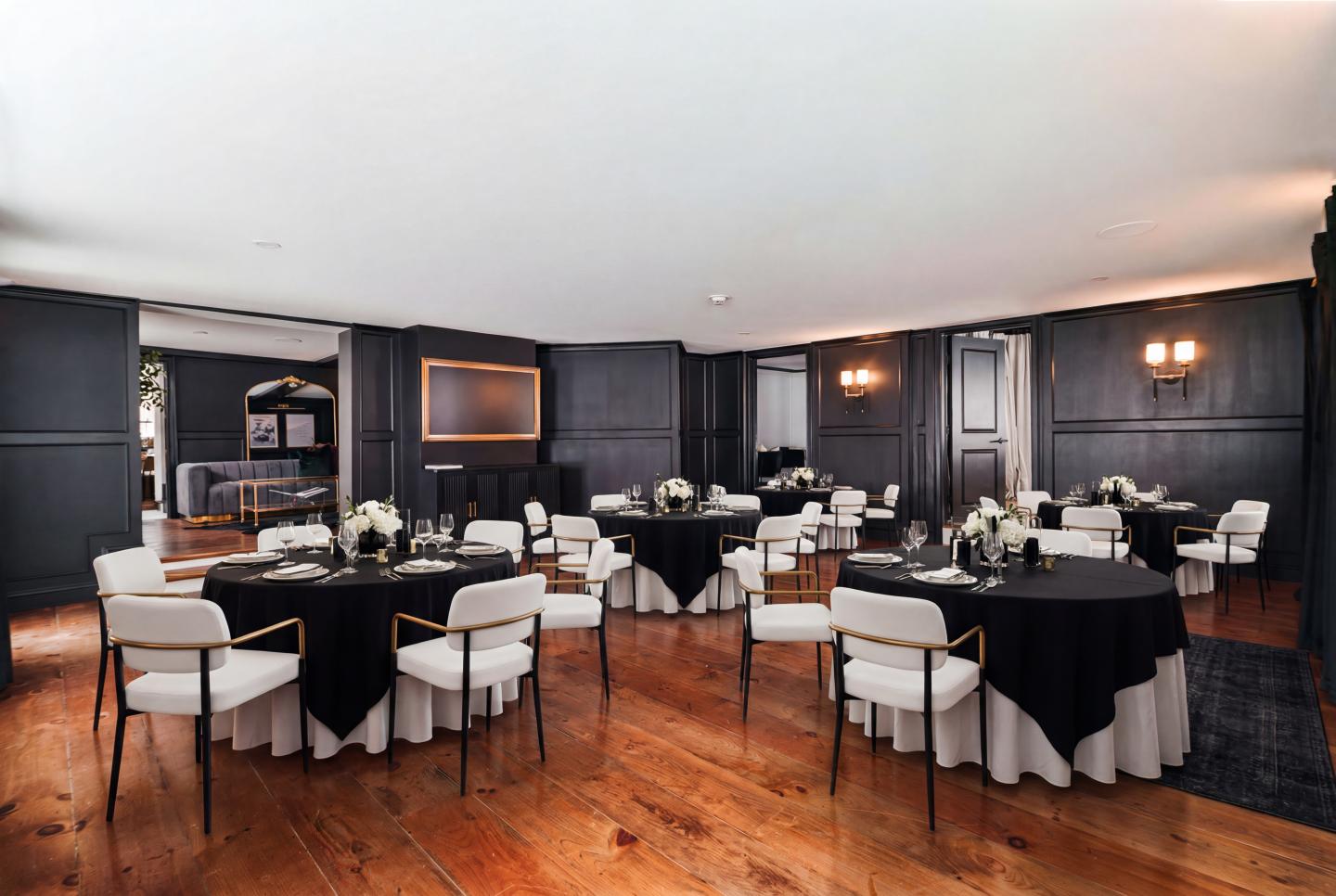 Elegant dining room with round tables, black tablecloths, and white chairs.