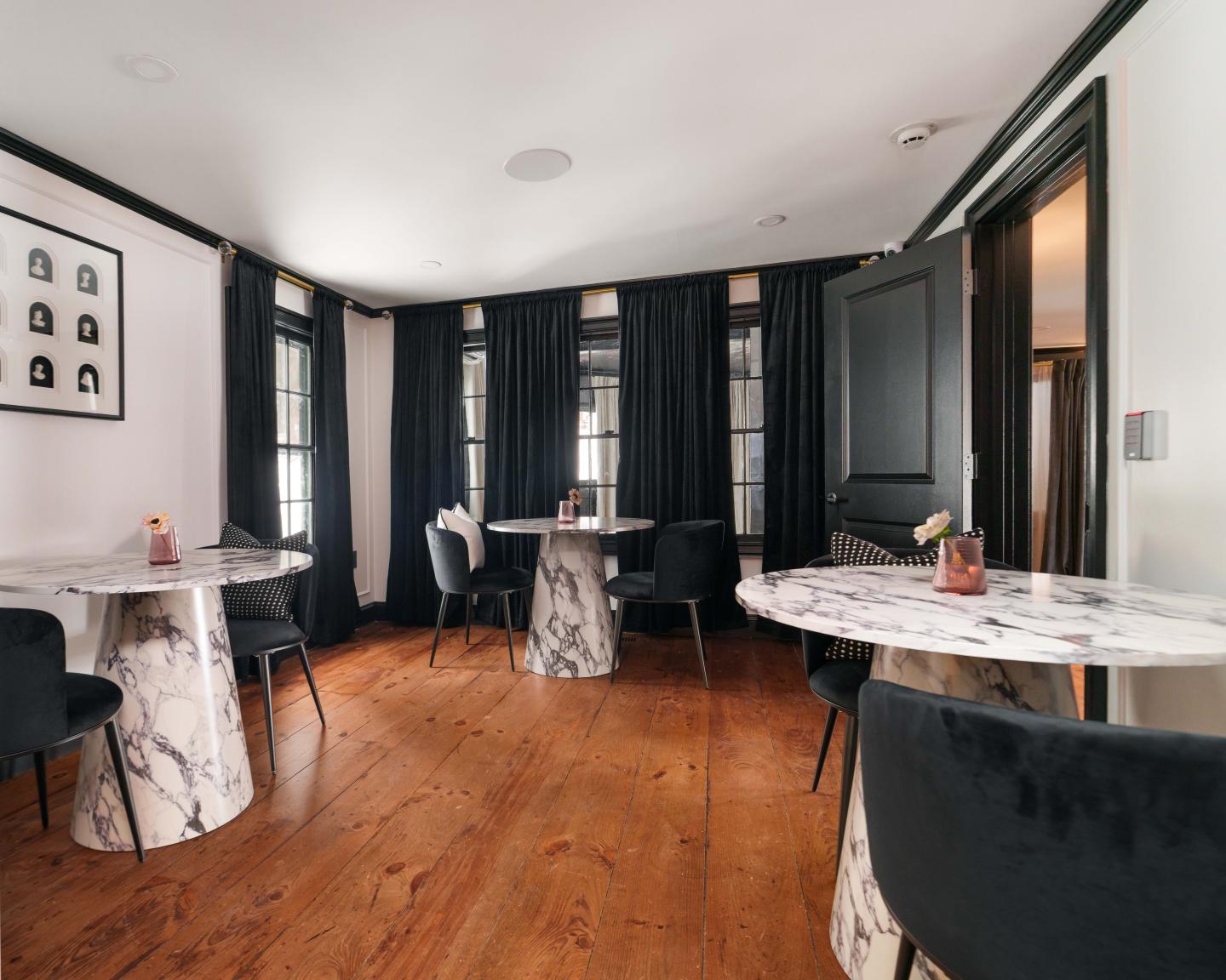 Cozy dining room with round marble tables and black curtains.