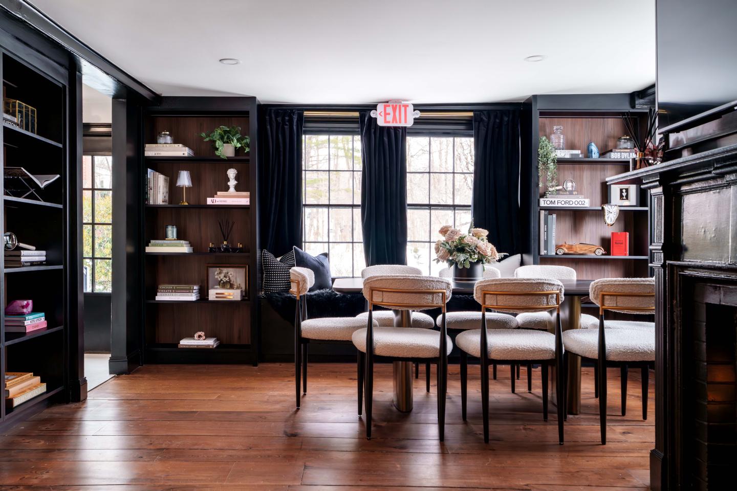 Cozy library with wooden shelves, a table, and chairs.