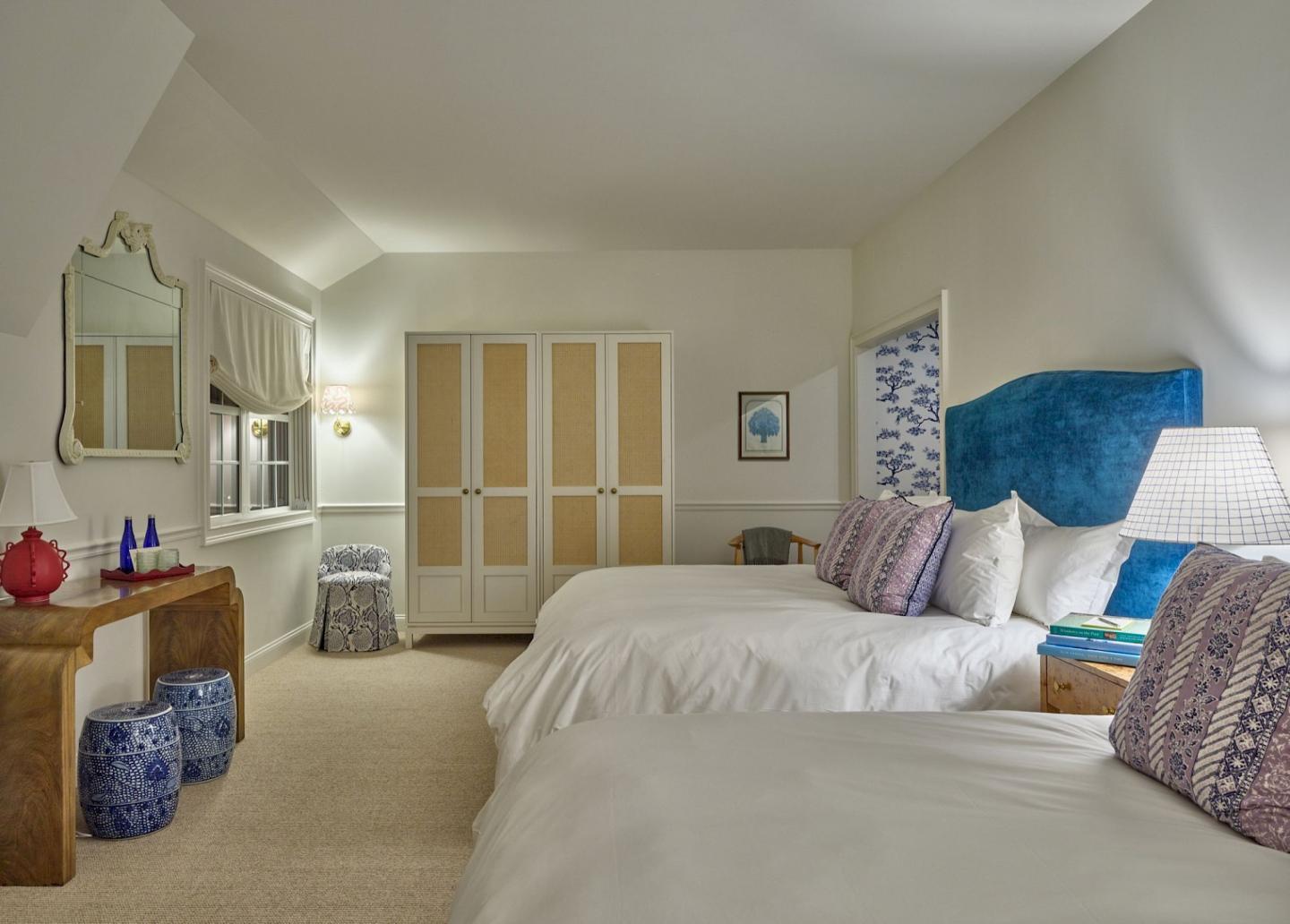 Two beds in a cozy bedroom, with blue and white decor and a wooden dresser.