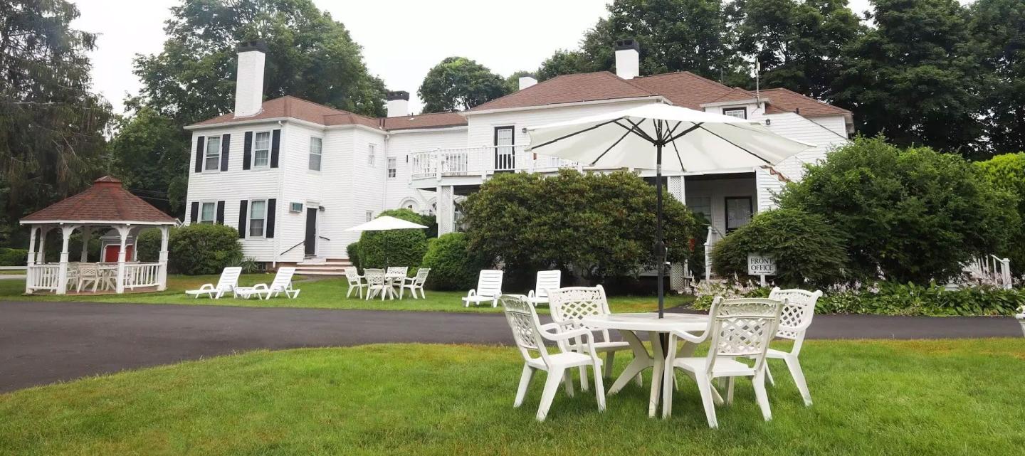 White house with gazebo, green lawn, and outdoor furniture.